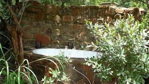 A stone-walled outdoor bathroom with a built-in sink and shower. - Forest Creek Lodge & Spa (Mashishing)