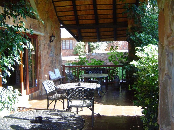 An outdoor patio area with stone walls, metal furniture, and potted plants.