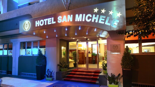 The entrance to Hotel San Michele with a lit sign, steps leading to the entrance, and potted plants around. - Hotel San Michele (Milazzo)