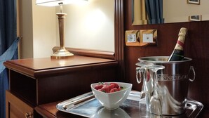 A hotel room with a wooden desk, a lamp, a tray with a bowl of strawberries, a champagne bottle, and glasses. - Hotel San Michele (Milazzo)