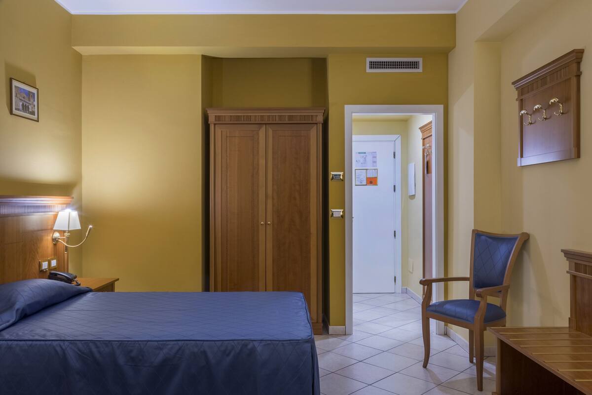 Une chambre d’hôtel comprenant un lit, une chaise, un bureau, une lampe et une armoire.
