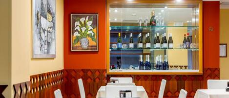 Un interior de restaurante con una zona de bar, mesas y sillas blancas.