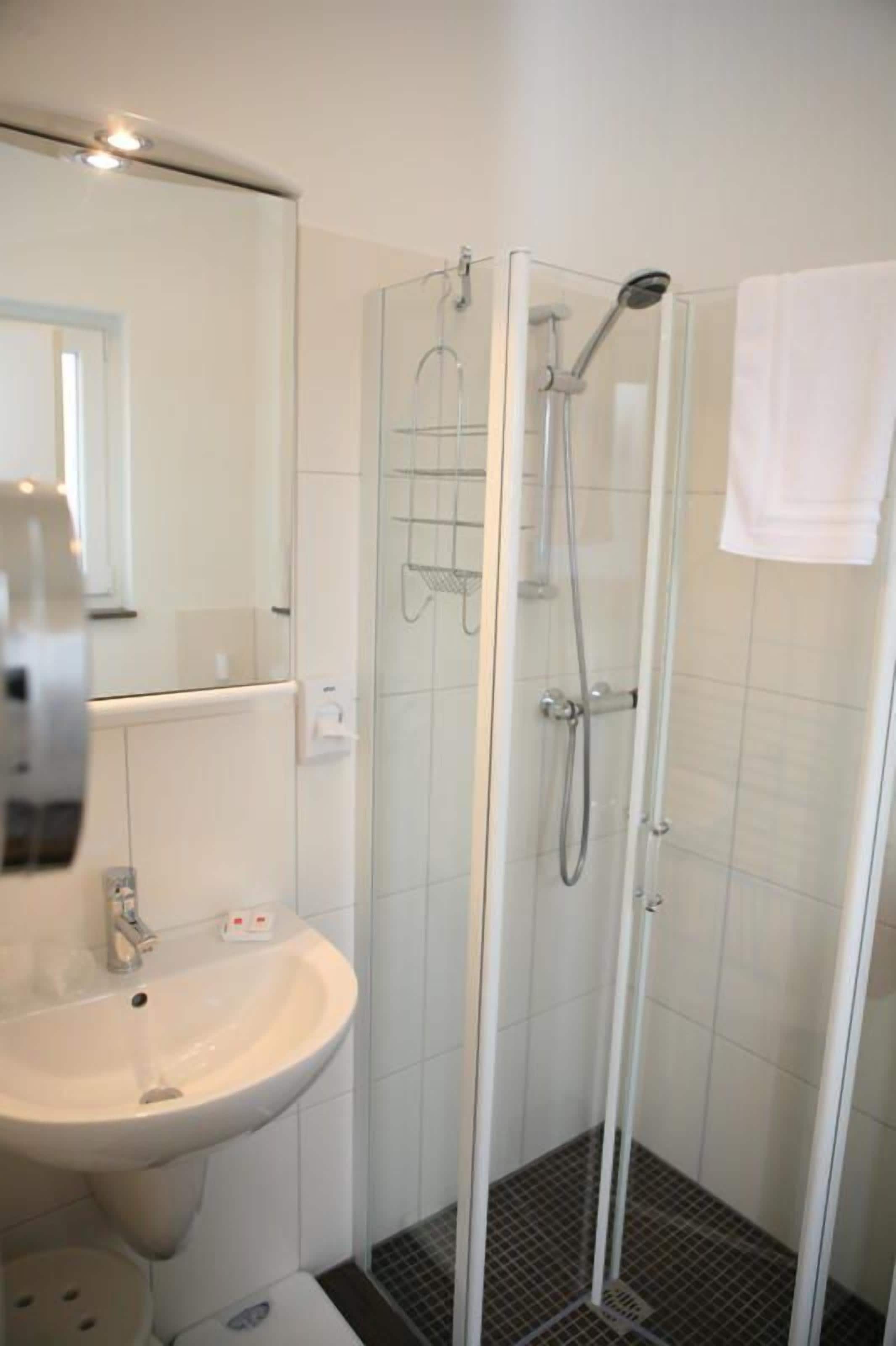 A bathroom with a glass-enclosed shower, a sink, and a mirror.