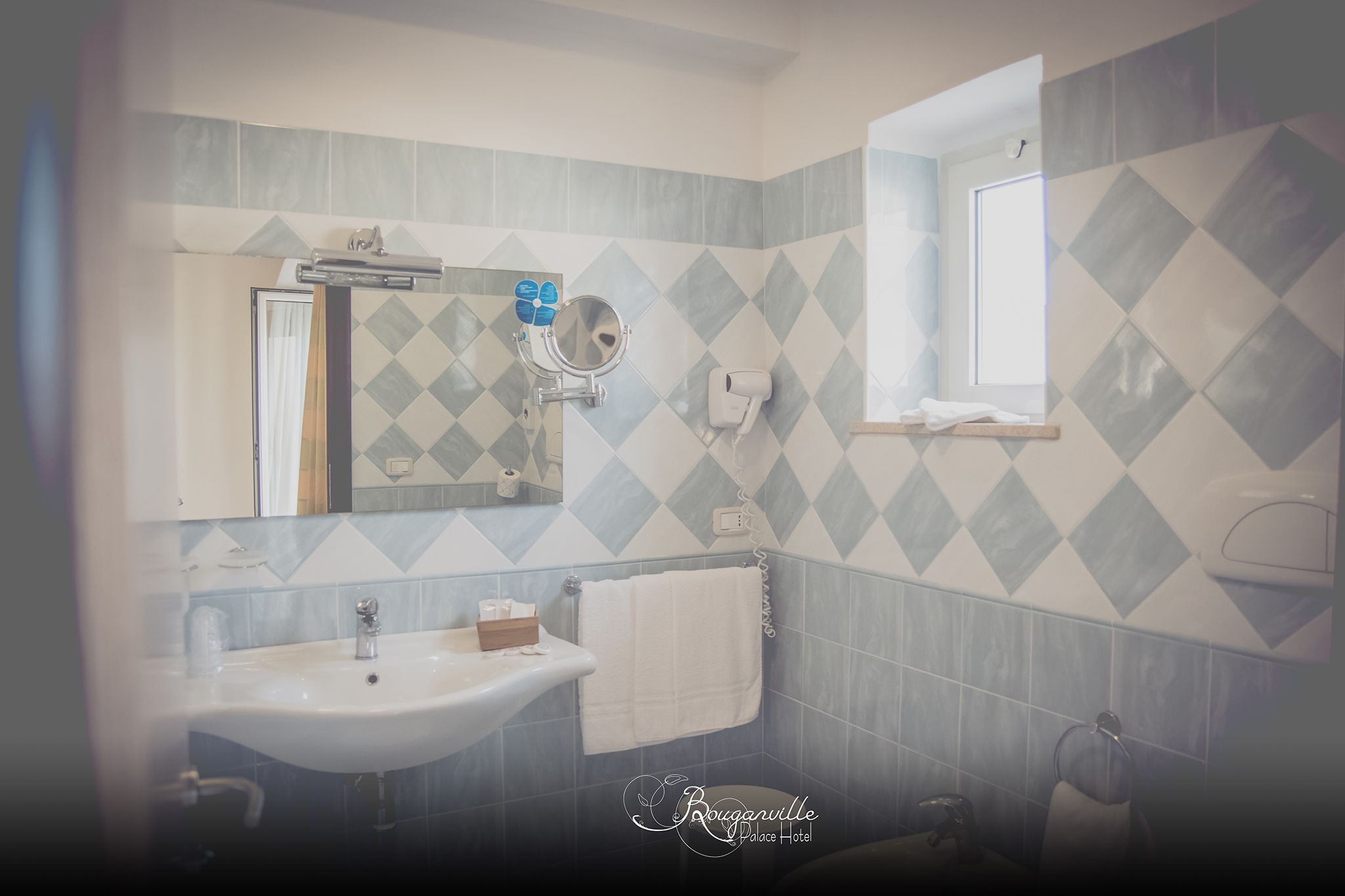 Een badkamer met een wastafel, spiegel en handdoekrek.
