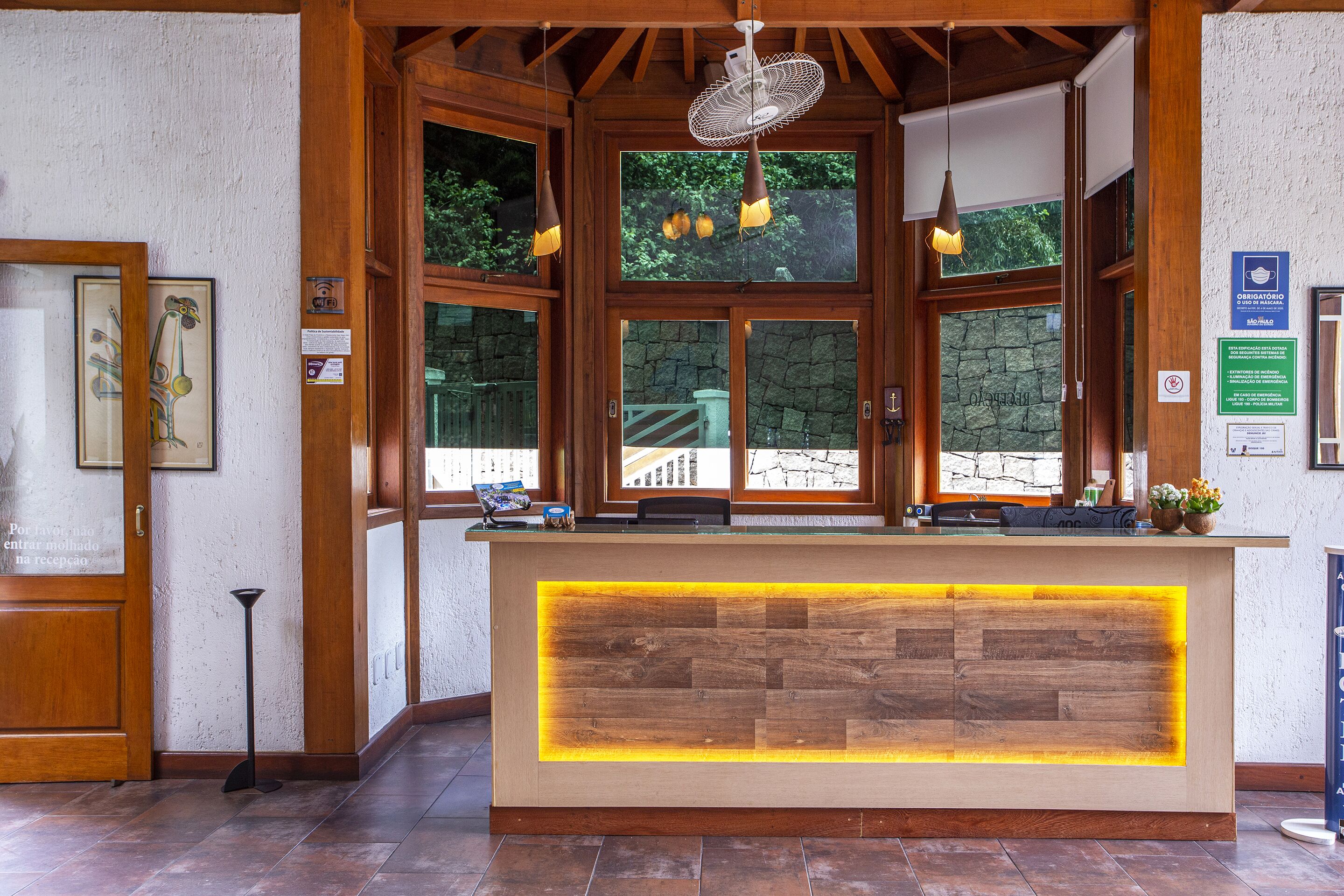 Un comptoir d’accueil avec un revêtement en bois et un panneau lumineux intégré.