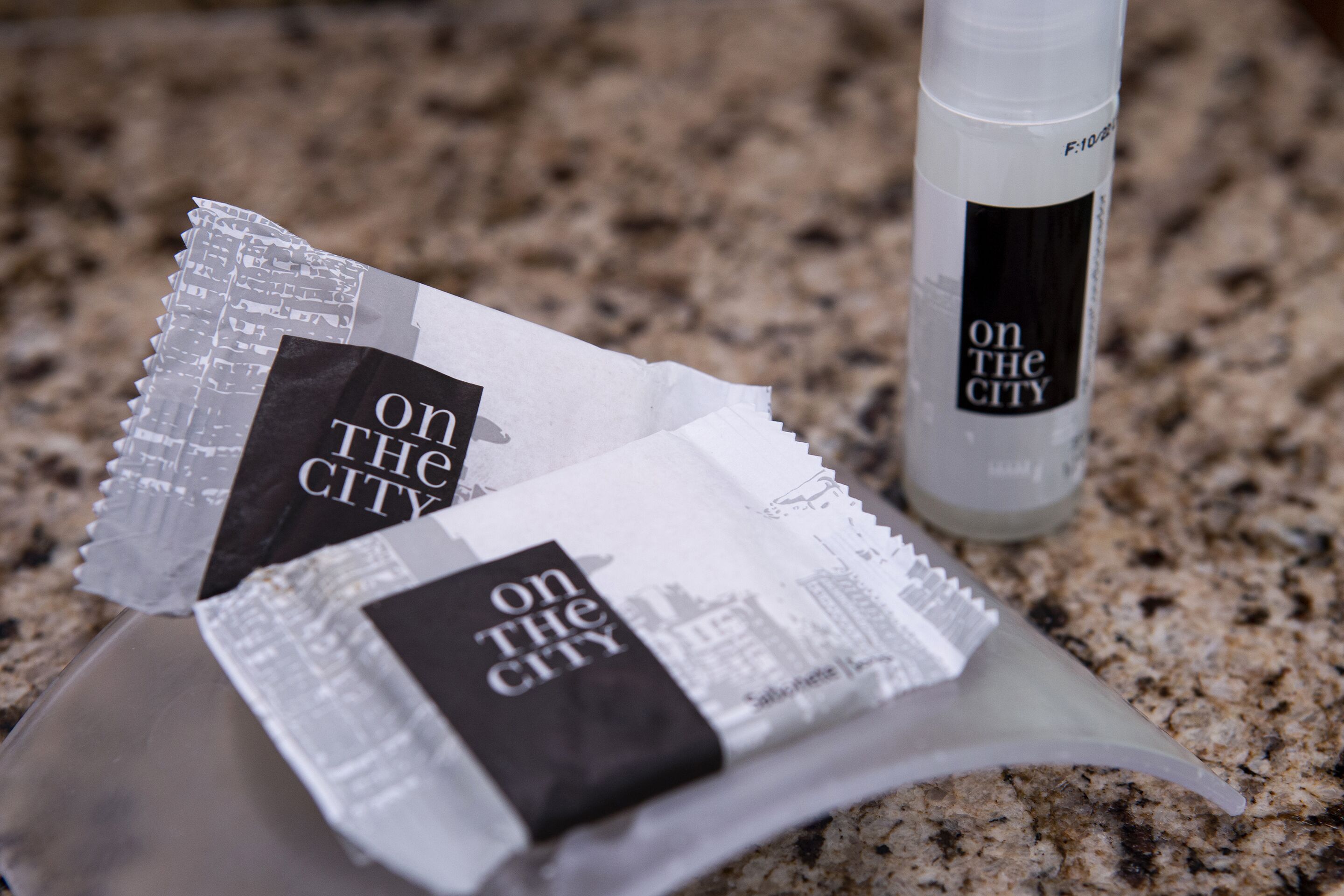 A bottle and two packets labeled "On the City" on a granite countertop.