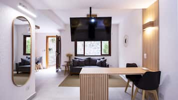 Un soggiorno moderno con un tavolo da pranzo in legno, sedie nere, un divano e una televisione.