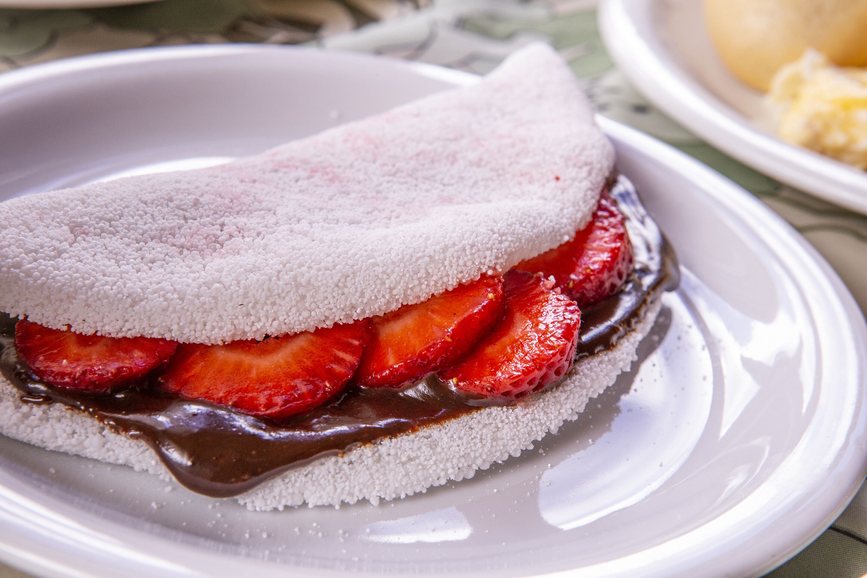 A dessert with a white, textured top layer, strawberries, and chocolate sauce.