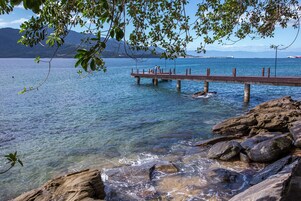 A pier extending into a calm body of water with clear water and rocky shores.