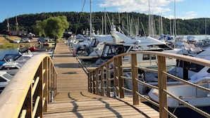 Een houten steiger die uitkomt bij een jachthaven met meerdere boten.