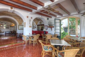 A spacious dining area with high ceilings, wooden beams, and wicker furniture. - Hotel del Almirante (Es Castell)