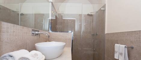 A modern bathroom with a large white sink, a glass-enclosed shower, and a towel rack.
