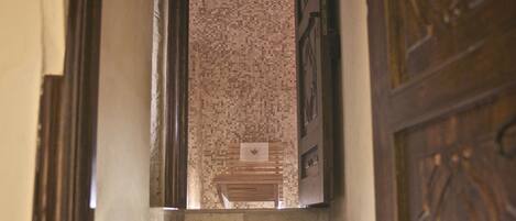Una escalera con un muro de diseño y una puerta de madera con tallas elaboradas.