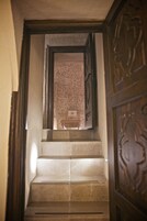 Una escalera con un muro de diseño y una puerta de madera con tallas elaboradas.