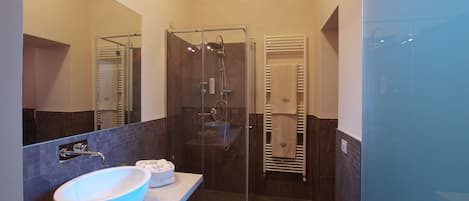 Un baño moderno con un lavamanos grande de color blanco, una ducha con cerramiento de vidrio y una bañera.