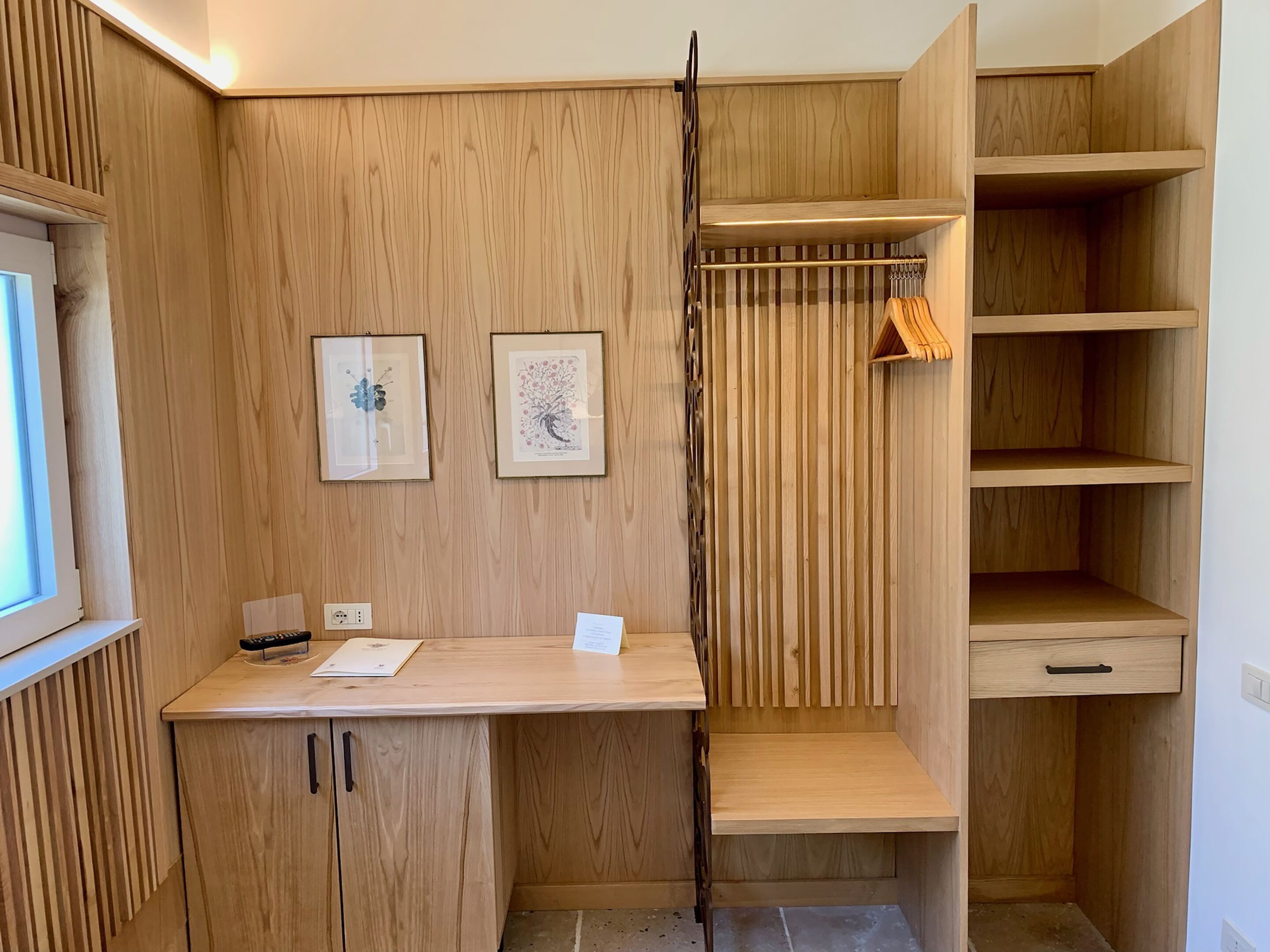 Een houten kamer met een bureau, twee ingelijste foto's en inbouwplanken.