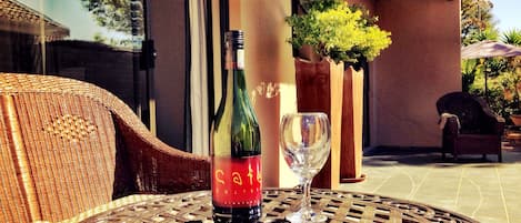 Una silla de mimbre y una mesa con una botella y un vaso encima.