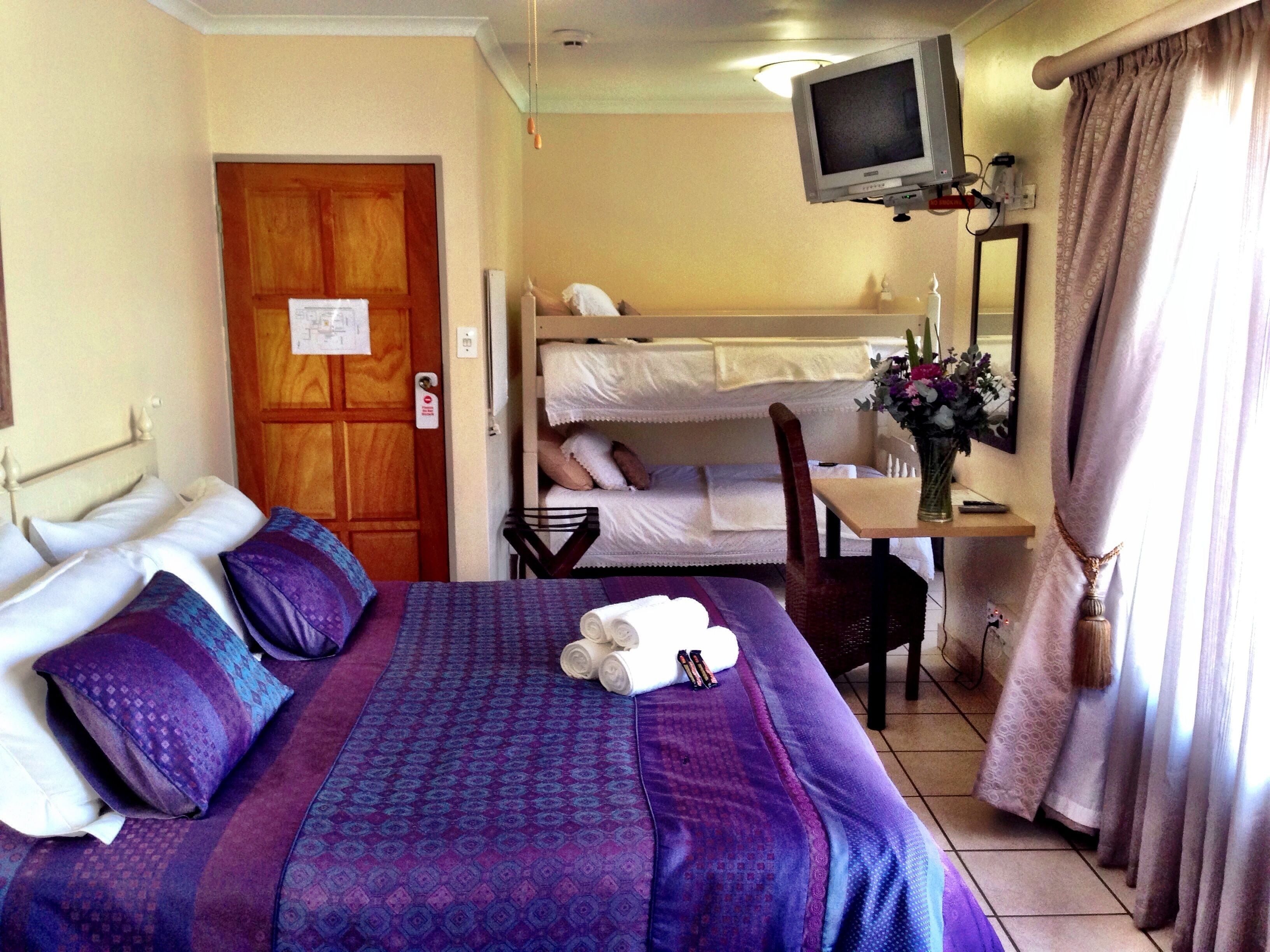 A hotel room with a bed, a desk, a chair, a television, and a window with curtains.
