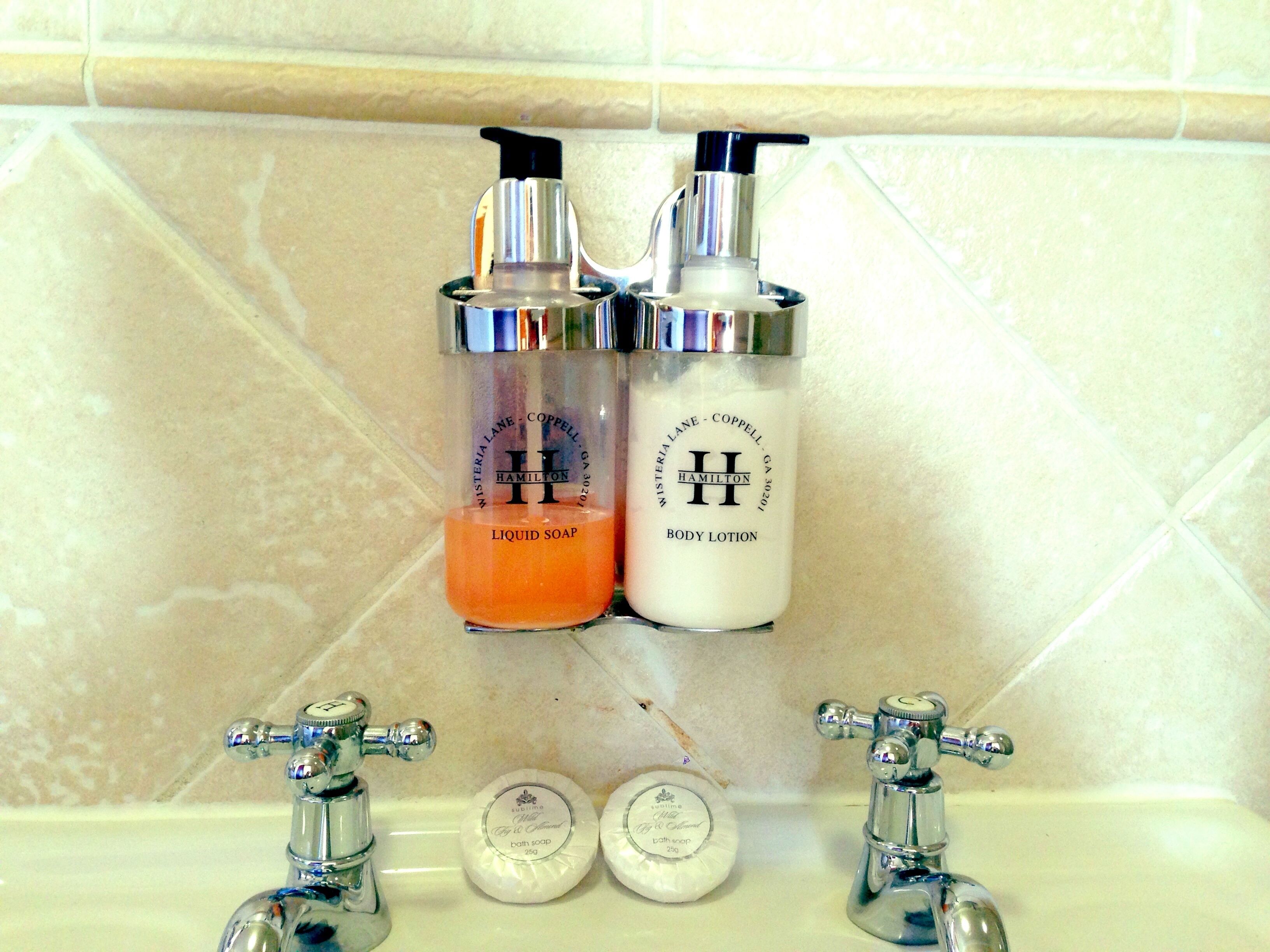 Une salle de bain équipée de deux distributeurs de savon portant l’inscription « Hamilton » et d’une paire de robinets.