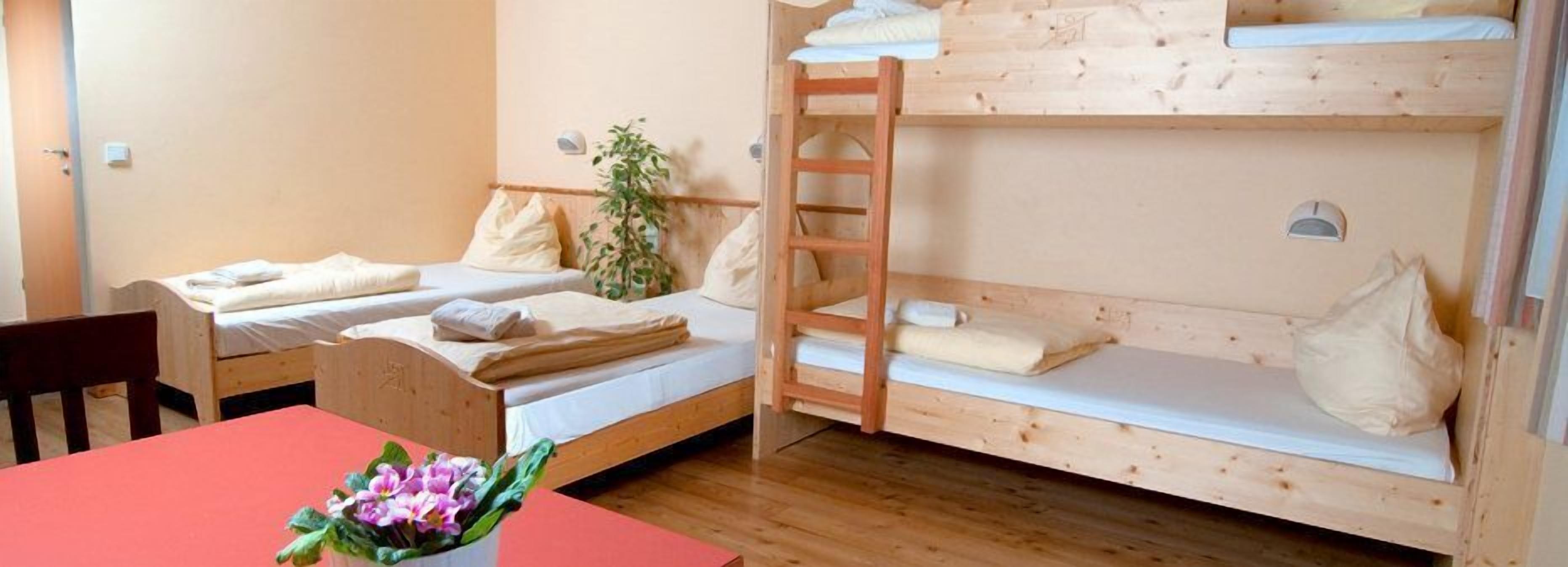Een kamer met twee stapelbedden, een houten tafel en een stoel.