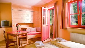 Una habitación acogedora con detalles de madera, una cama, una mesa con una silla y un televisor.