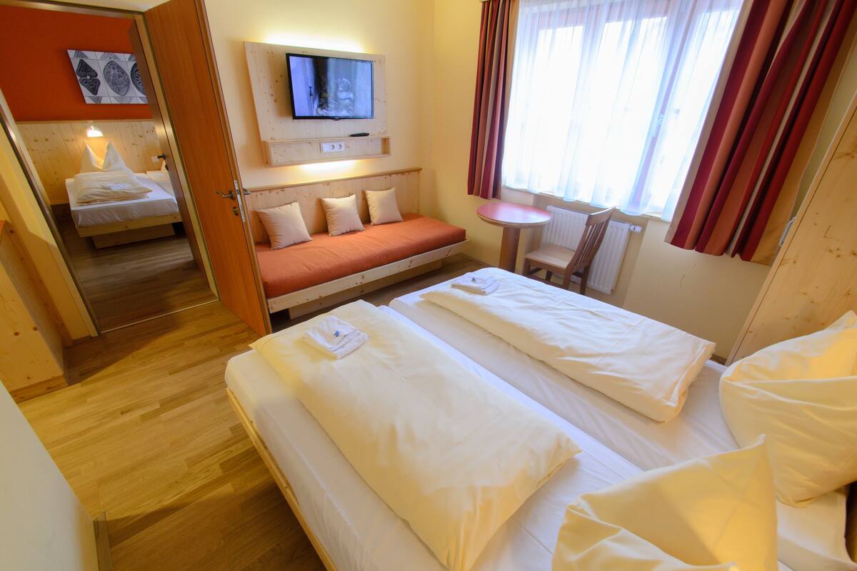 A hotel room with two beds, a television, a small table, and a chair.