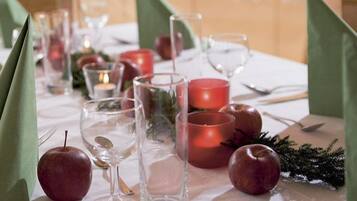 Una mesa preparada para una comida, con servilletas verdes, manzanas rojas y vasos transparentes.