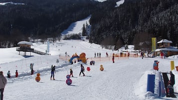 Une station de ski avec une piste enneigée, un télésiège et un paysage montagneux en toile de fond.