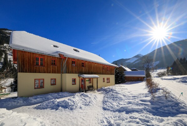 Un edificio de madera con techo nevado y un pequeño porche.