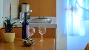 A wooden table with a potted plant, a bottle of wine, and two wine glasses. - Studio Apartments Stradun (Dubrovnik)