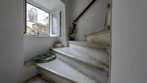 A set of worn concrete stairs leading to a landing with a window overlooking a building. - Studio Apartments Stradun (Dubrovnik)