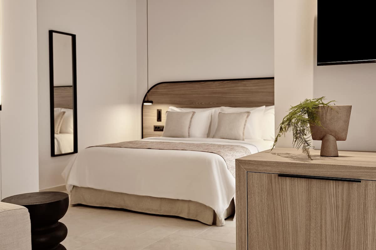 A modern bedroom with a bed, bedside table, and a TV mounted on the wall.