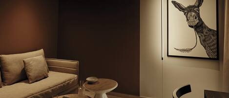 Una sala moderna con un sofá, dos mesas auxiliares, una mesa de comedor y una obra de arte enmarcada en la pared.