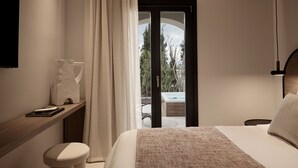 Un dormitorio moderno con una cama grande, una mesita de noche, una silla y vistas a un área exterior con un jacuzzi.