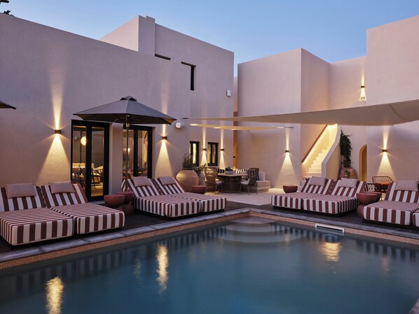 Una piscina al aire libre, sillones reclinables de piscina