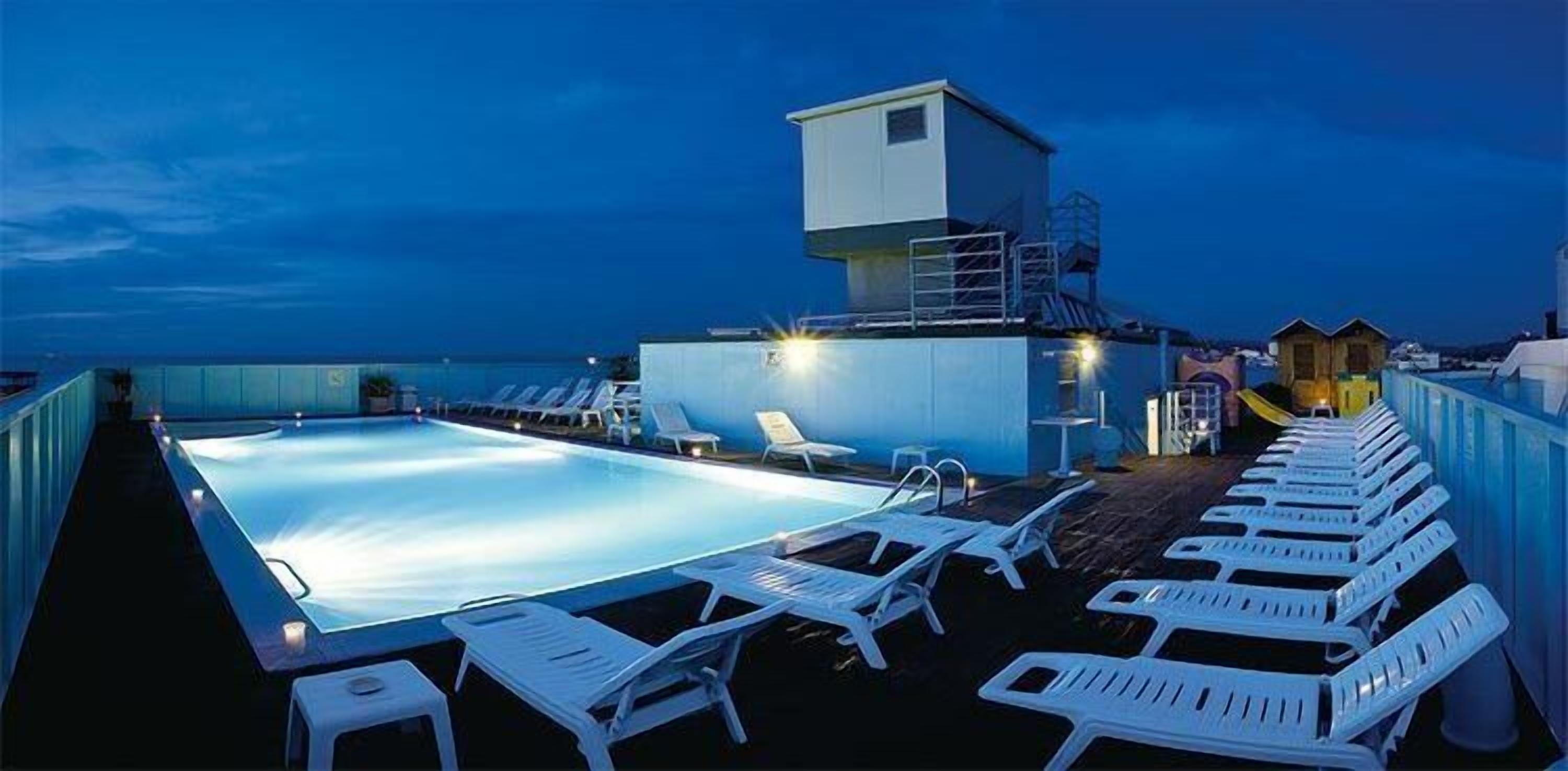 A rooftop pool area with lounge chairs and a lifeguard tower.