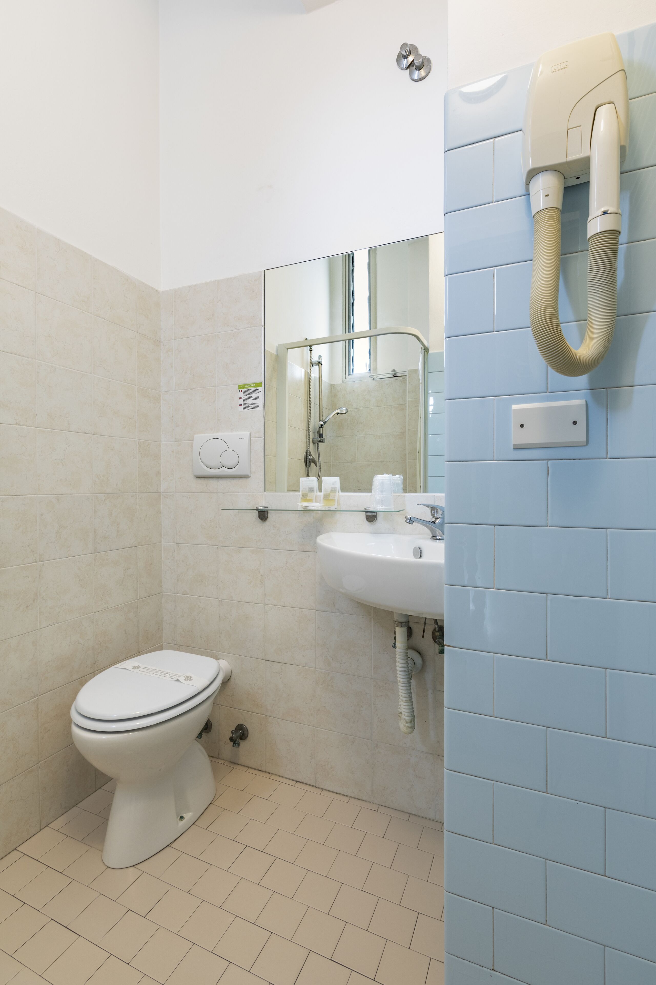 A bathroom with a toilet, sink, and a hand dryer mounted on the wall.