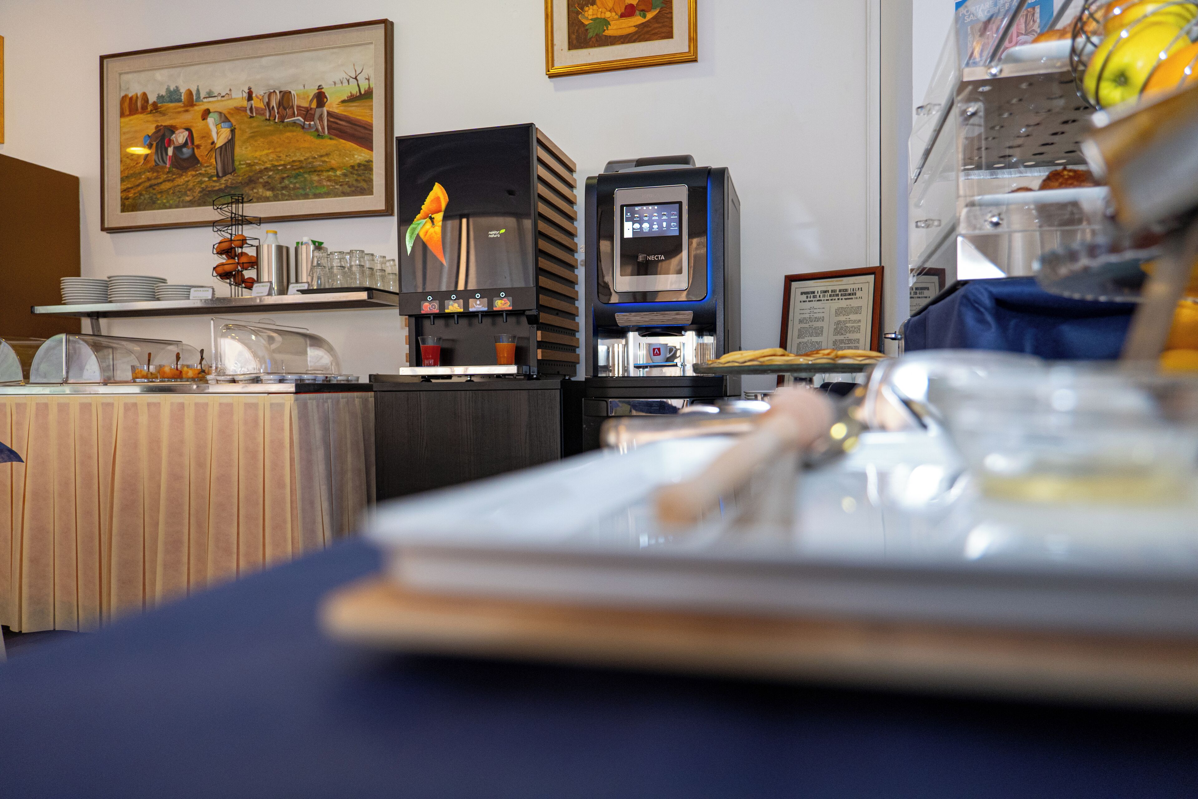 A kitchen area with a coffee machine, a food display, and a table with a placemat.