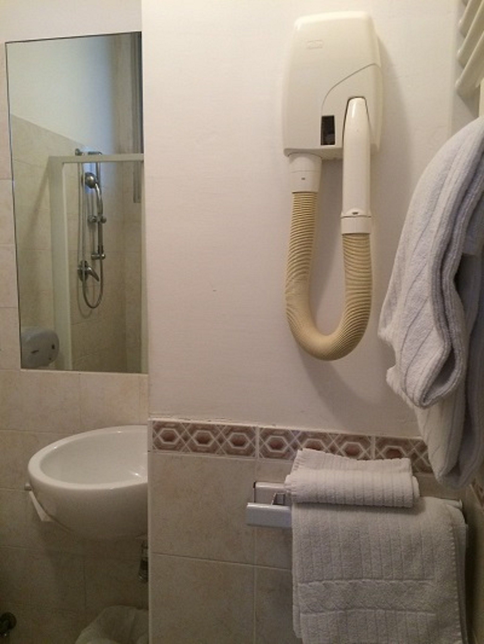 A bathroom with a toilet, a sink, a towel rack, and a hand dryer.