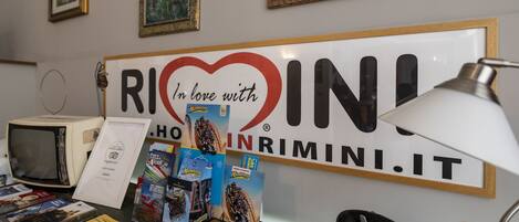 Un escritorio con un letrero que dice "In love with RIMINI.IT" y varios folletos de viaje.