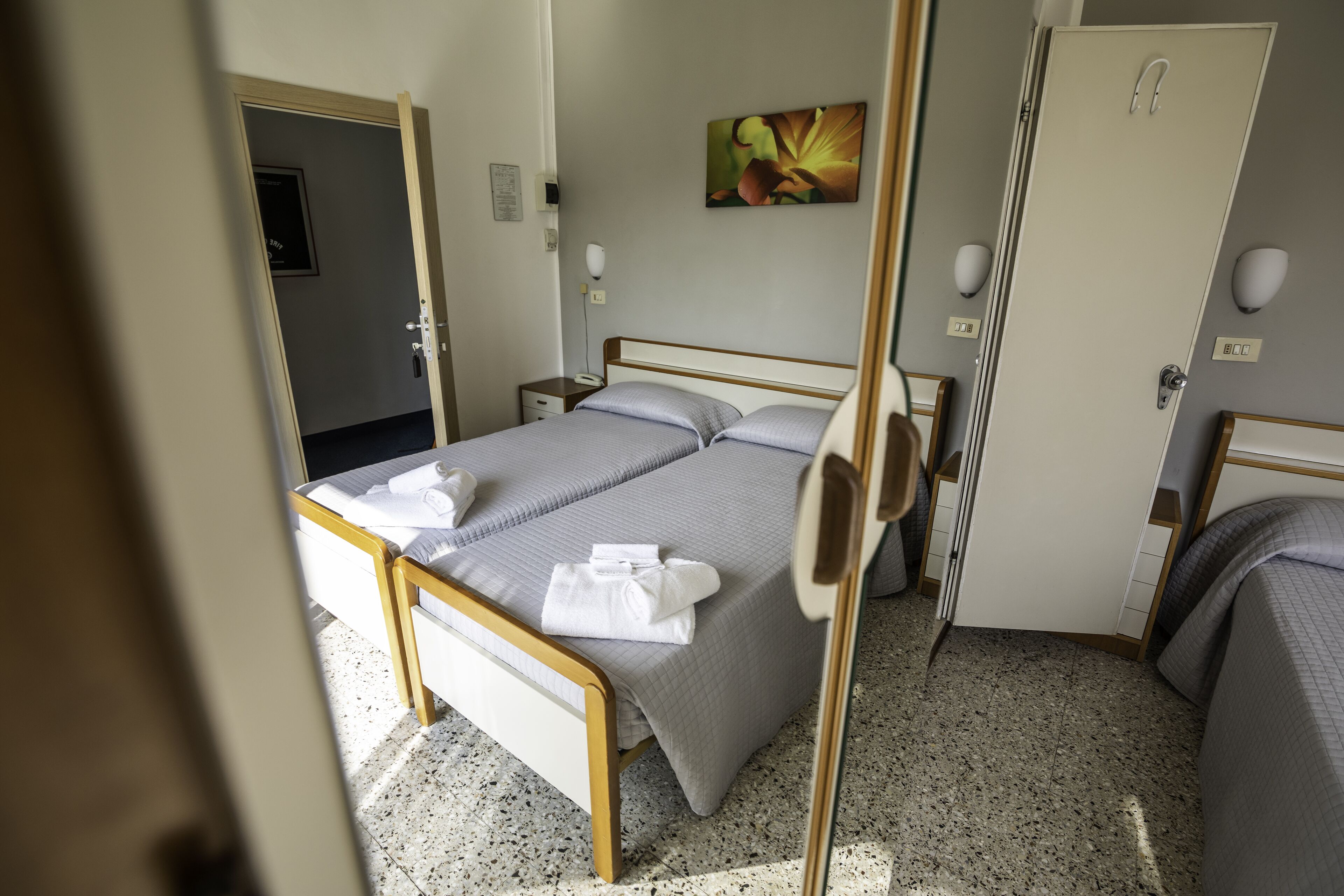 Ein Hotelzimmer mit Bett, Nachttischen, einer Tür und einem Bild an der Wand.