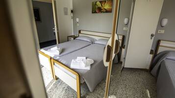 Ein Hotelzimmer mit Bett, Nachttischen, einer Tür und einem Bild an der Wand.