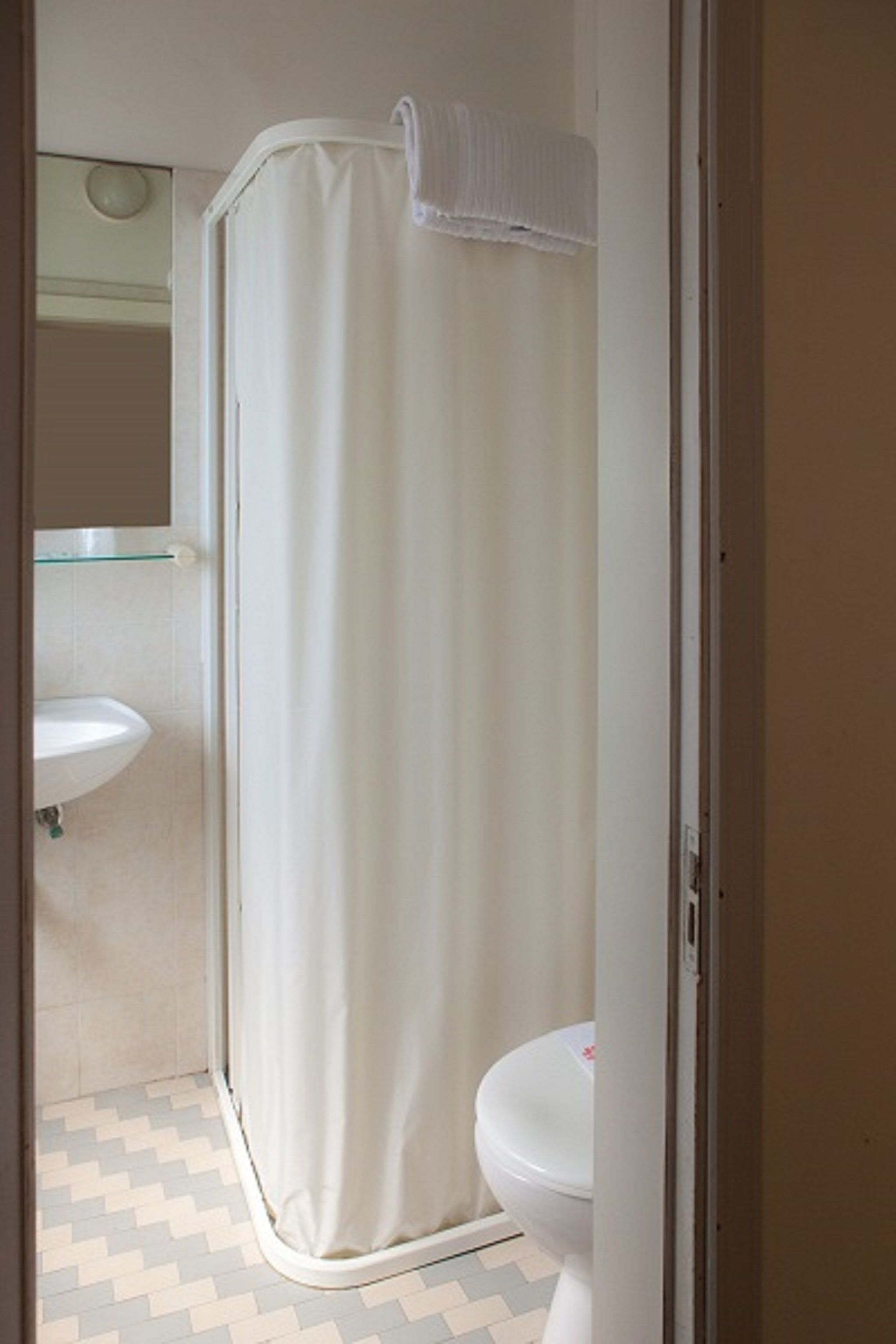 A bathroom with a shower curtain, a sink, and a toilet.
