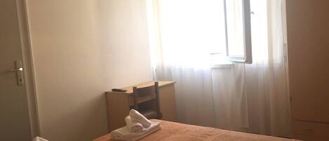 Une chambre d’hôtel avec un lit, un bureau, un téléviseur fixé au mur et une fenêtre avec des rideaux.