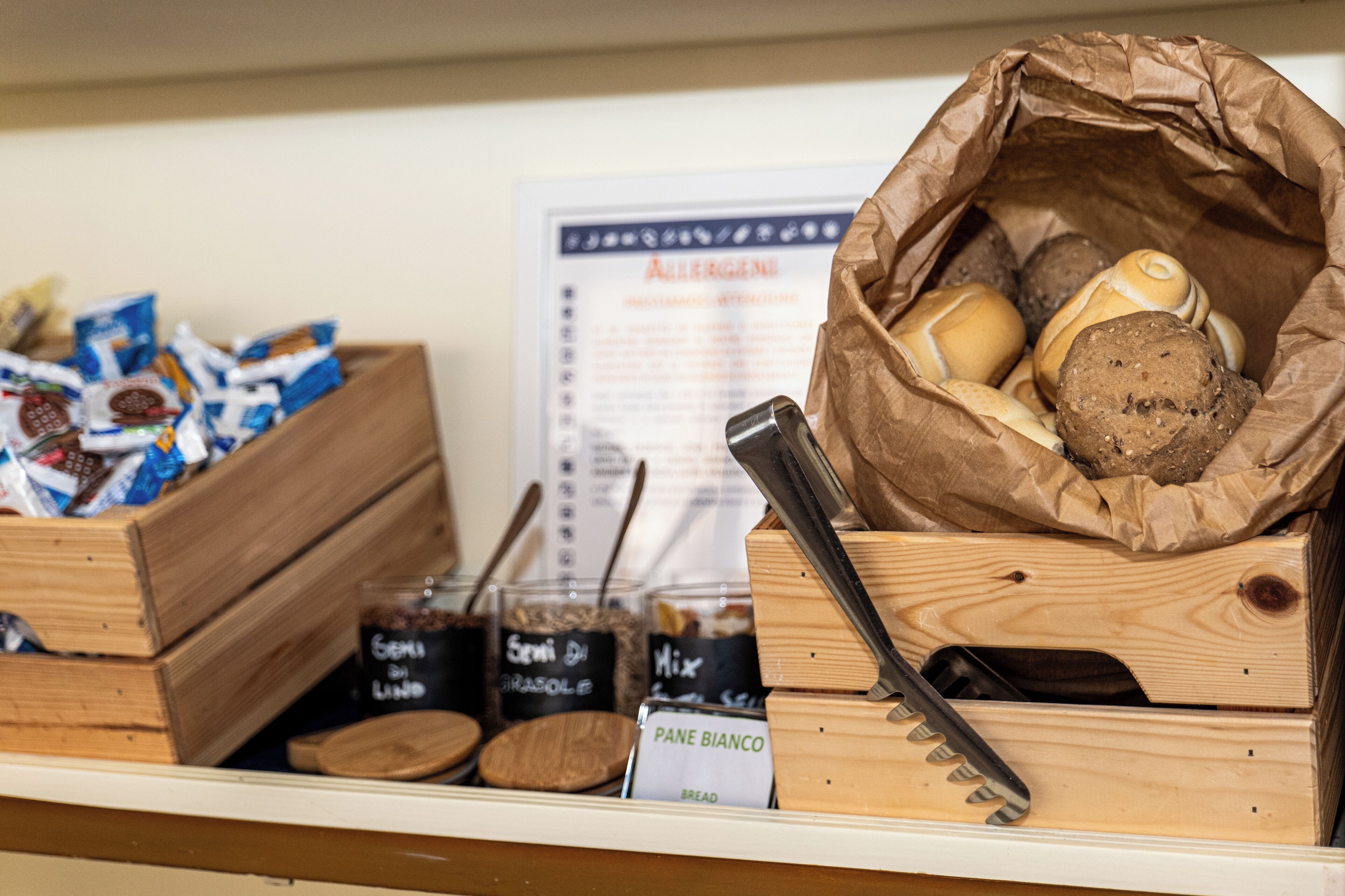 A bakery display with various bread types and a sign indicating 'PANE BIANCO'.