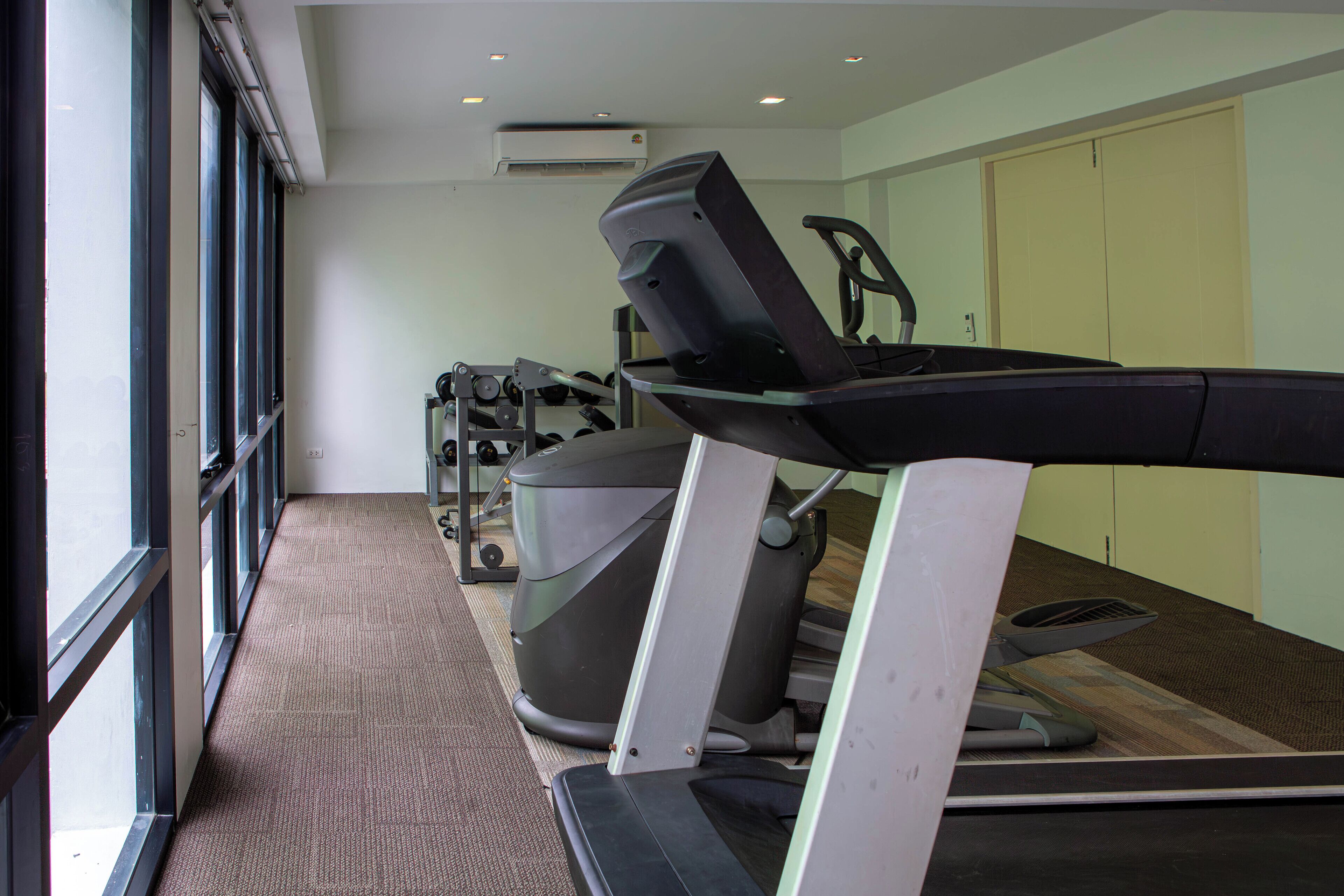 Un gimnasio con cintas de correr, una bicicleta estática y una máquina de remo.