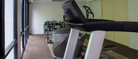 Un gimnasio con cintas de correr, una bicicleta estática y una máquina de remo.