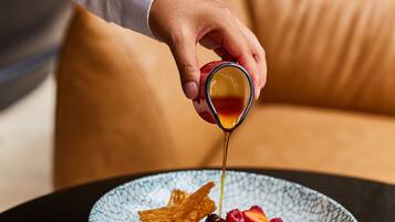 A dessert being topped with syrup on a plate.