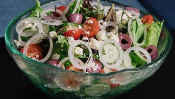 A bowl of salad on a dark surface.