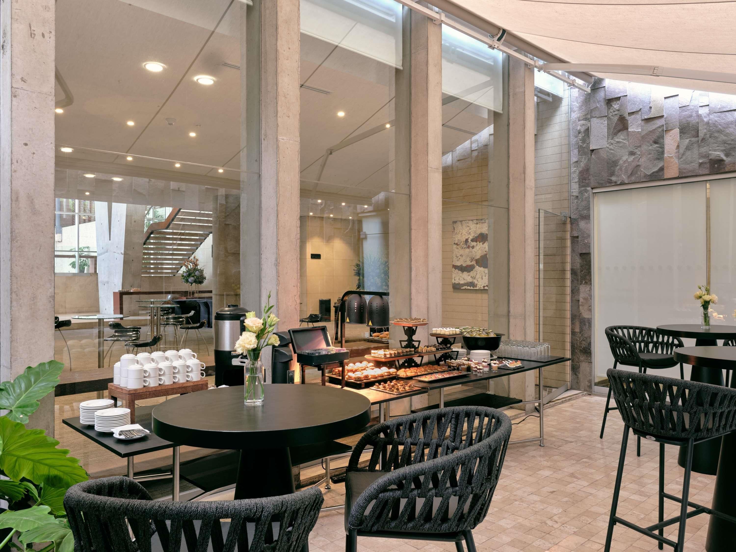Un comedor interior moderno con techos altos, ventanas amplias y diversas opciones de asientos.